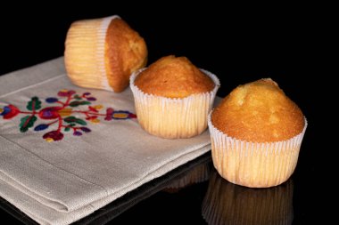 Üç küçük kekten oluşan bir grup siyah camla izole edilmiş keten kumaş üzerinde.