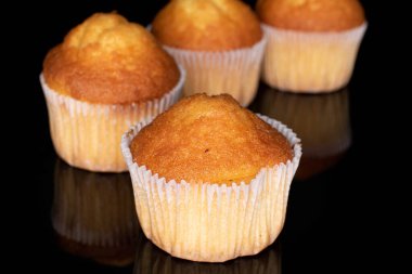 Dört küçük kekten oluşan bir grup, siyah camda izole edilmiş.