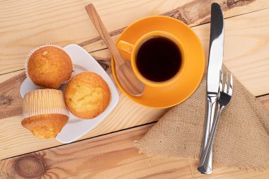 Üç küçük kekten oluşan bir grup ve kahvaltıda kahveleri ahşap.