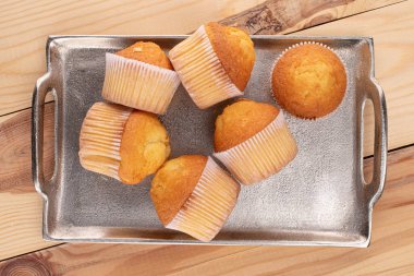 Tahtadaki tepside altı küçük kek grubu.