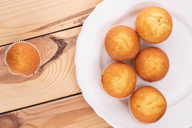 Altı küçük kekten oluşan bir grup porselen tabakta ahşap üzerinde