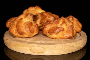 Tahta tabakta, siyah camla izole edilmiş taze pişmiş beş profiterol grubu.