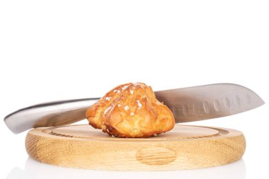 Taze pişmiş bir profiterol, beyaz üzerine izole edilmiş ahşap bir tabakta bıçak.