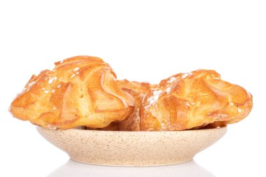 İki taze profiterol grubu seramik tabakta beyaz üzerine izole edilmiş.