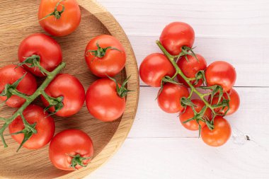 Bir sürü taze kırmızı kiraz domatesi beyaz ahşap bambu tabakta