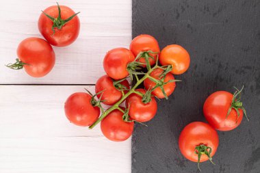 Bir sürü taze kırmızı kiraz domatesi beyaz ahşap üzerinde gri taş