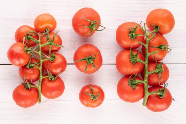 Bir sürü taze kırmızı kiraz domatesi beyaz ahşap sarmaşıklarda