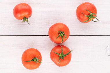 Beyaz ahşap üzerinde beş tane taze kırmızı kiraz domatesi.
