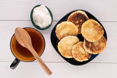 Ekşi kremalı altı tam peynirli krep ve beyaz ahşap çay fincanı.