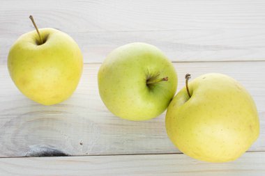 Üç büyük yeşil elma grubu beyaz ahşap üzerinde