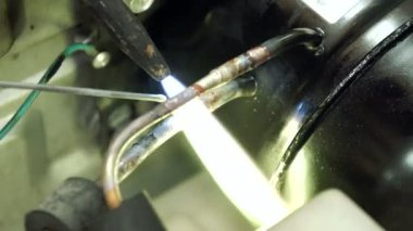 Servis Merkezi. Elektronik Onarım. Bir adam buzdolabı onarır. Alüminyum lehimleme.