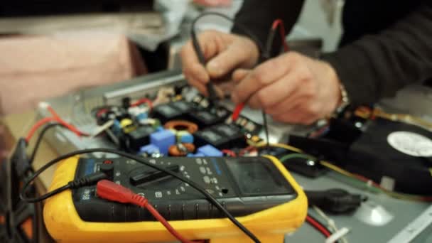 Centro de servicio. Talleres de electrónica. Un hombre repara la encimera. Multímetro . — Vídeos de Stock