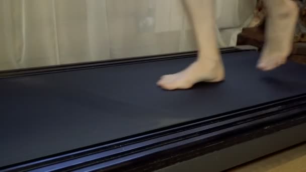 La ragazza va a piedi nudi sul tapis roulant. Primo piano . — Video Stock