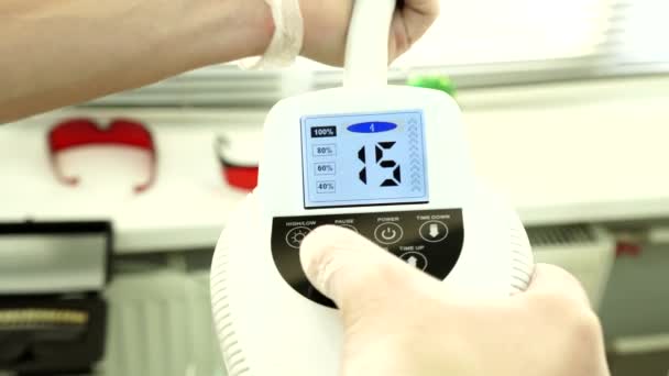 Le médecin ajuste la machine pour le blanchiment des dents. Clinique de blanchiment des dents .