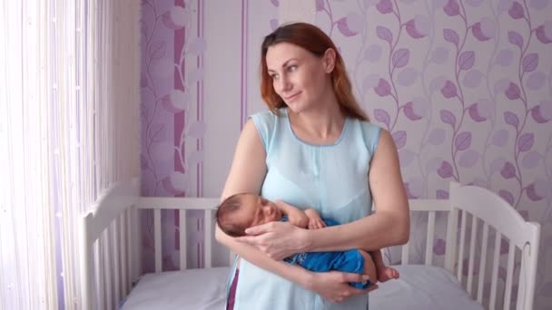 Μια νεαρή μητέρα λικνίζοντας ένα νεογέννητο στην αγκαλιά της. — Αρχείο Βίντεο