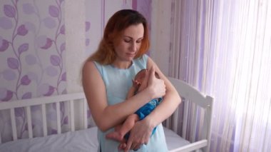 Yeni doğmuş bir bebek kucağında sallanan genç bir anne.