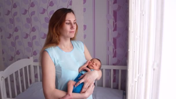 Yeni doğmuş bir bebek kucağında sallanan genç bir anne. — Stok video