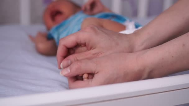 Νεαρή μητέρα βάζει κοριστίστικα παπουτσάκια νεογέννητο. — Αρχείο Βίντεο