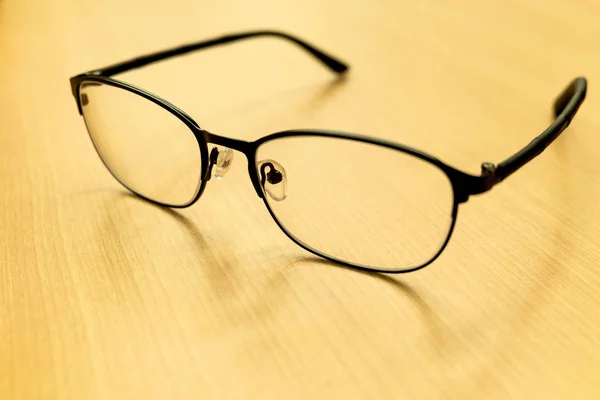 Tahta masa arkasında seçici odaklı gözlükler, masaya yerleştirilmiş gözlükler. — Stok fotoğraf