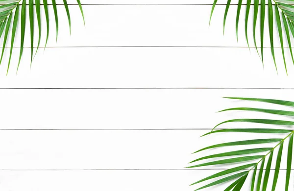 Grüne Palmenblätter auf weißem Holztischhintergrund, tropische grüne Palmenblätter, Draufsicht, flache Lage. — Stockfoto
