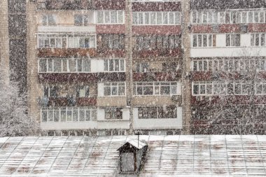 Büyük bir şehirde kar yağışı, karın altında bir apartman.