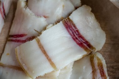 Tuzlanmış domuz yağı, ince ince dilimler halinde dilimlenmiş, Ukraynalıların ulusal yemeği, parşömen üzerindeki ahşap masada lezzetli domuz yağı.