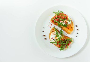 Lezzetli haşlanmış yumurta, beyaz bir tabakta domates, roka, baharat ve karabiber dilimli buğday dilimli ekmek.