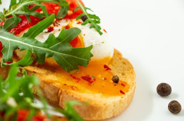 Lezzetli haşlanmış yumurta, beyaz bir tabakta domates, roka, baharat ve karabiber dilimli buğday dilimli ekmek.