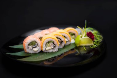 Sade yeşil arka planda Japon mutfağı suşisi. Sezar salatası ve arka planda sağlam bir makarna için karides fotoğrafı.