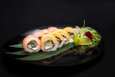 Sade yeşil arka planda Japon mutfağı suşisi. Sezar salatası ve arka planda sağlam bir makarna için karides fotoğrafı.