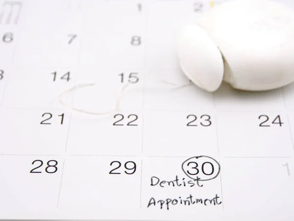 dentist appointment reminder on calendar with dental floss ; medical concept