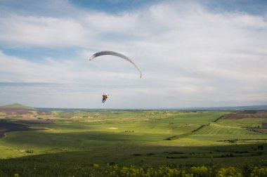 Paraglider flying above field clipart