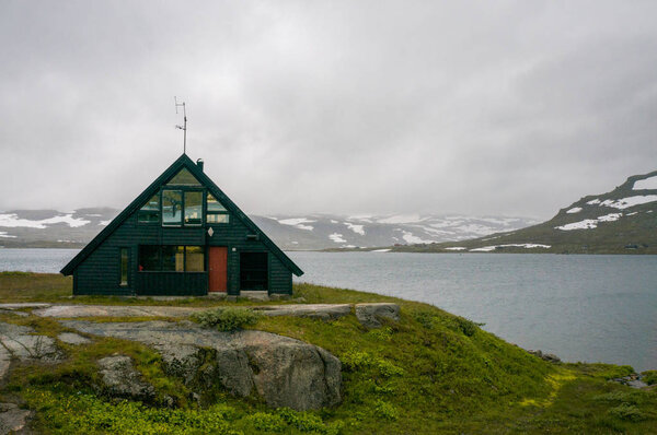 дом на лугу с горами и рекой
