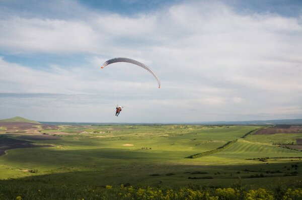Paraglider flying above field