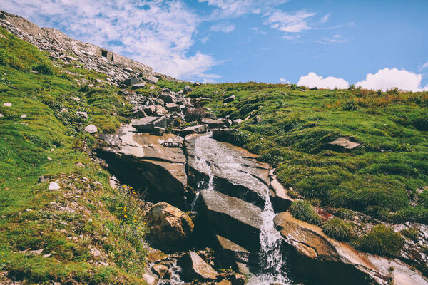 beautiful small waterfall on rocks and green grass in Indian Himalayas, Rohtang Pass  