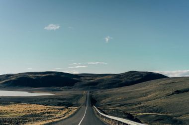 empty asphalt road between scenic hills in Iceland clipart
