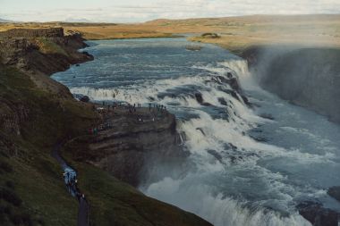 group of tourists looking at majestic waterfall in Iceland  clipart