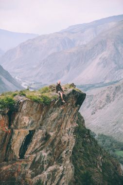 Cliff üzerinde oturan ve görkemli Dağları, Altay, Rusya bakıyorsun adam  