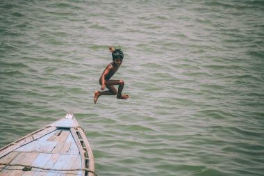 Varanasi, Hindistan tekneden atlama sevimli küçük çocuk