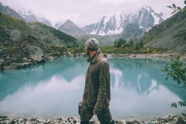 side view of man looking at majestic calm mountain lake in Altai, Russia clipart