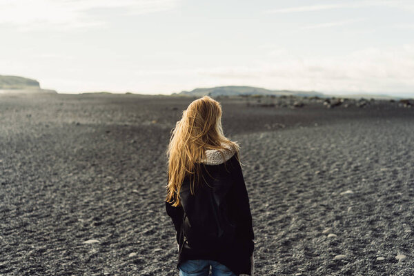 back view of young woman looking at beautiful wild icelandic landscape