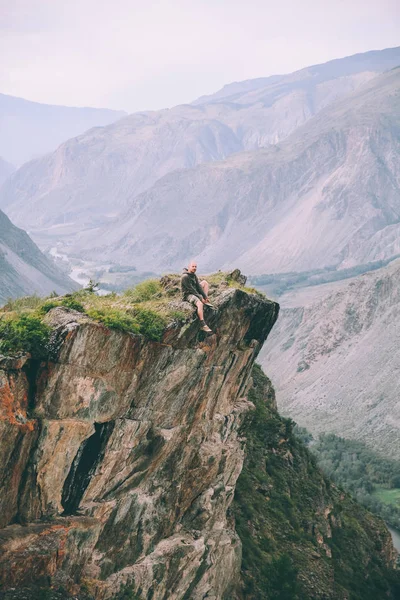男は崖の上に座って アルタイ ロシアの雄大な山々 を見て — ストック写真