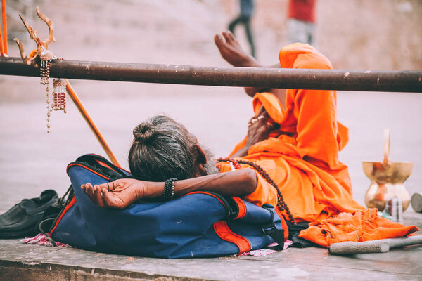 monk in bright orange clothing resting in Varanasi, India