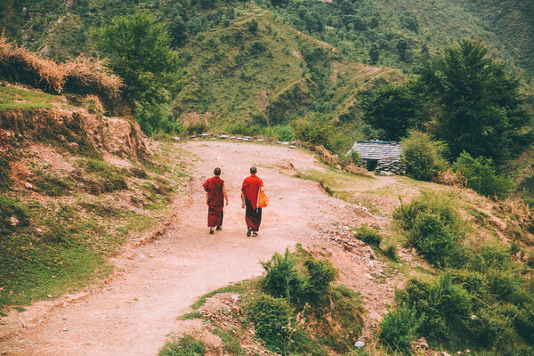 back view of two monks walking on mountain road in Indian Himalayas, Dharamsala, Baksu