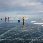 Grupo de turistas em pé na superfície da água gelada durante o dia, Rússia, lago baikal