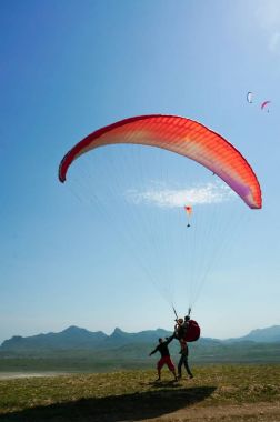 Two men parachuting on field with hills on backgrond, Crimea, Ukraine clipart