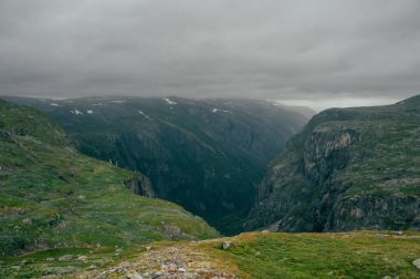 grassy slopes of rocks during foggy weather, Norway, Hardangervidda National Park clipart