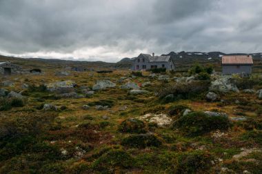 çim ve taş evlerin altında fırtınalı gökyüzü, Norveç, Hardangervidda'da Milli Parkı