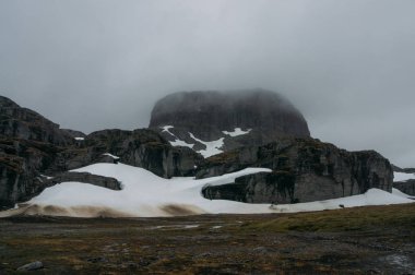 view of rock formation with snow  during foggy weather, Norway, Hardangervidda National Park clipart
