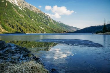 view of mountain lake with trees on slopes of mountain over water, Morskie Oko, Sea Eye, Tatra National Park, Poland
